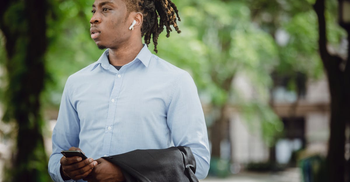 How to call emergency meeting on the Submerged map? - Stylish black businessman in TWS earbuds with smartphone waiting for meeting in park