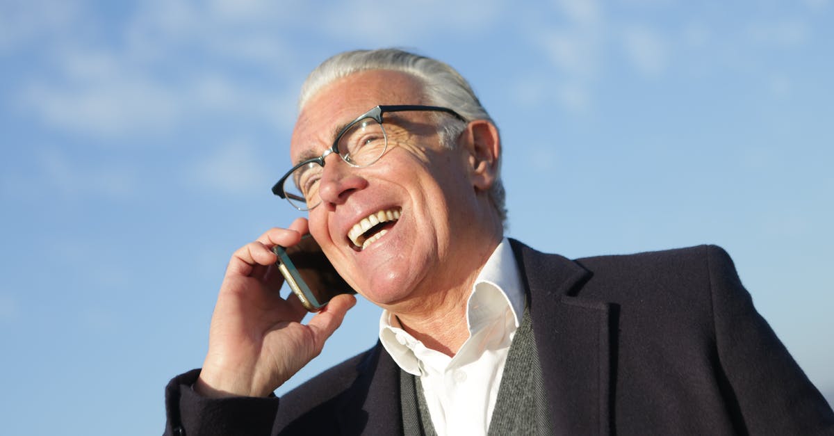 How to chat to all - From below of delighted aged male entrepreneur in classy outfit standing on street and speaking on cellphone while laughing and looking away How to chat to all - From below of delighted aged male entrepreneur in classy outfit standing on street and speaking on cellphone while laughing and looking away