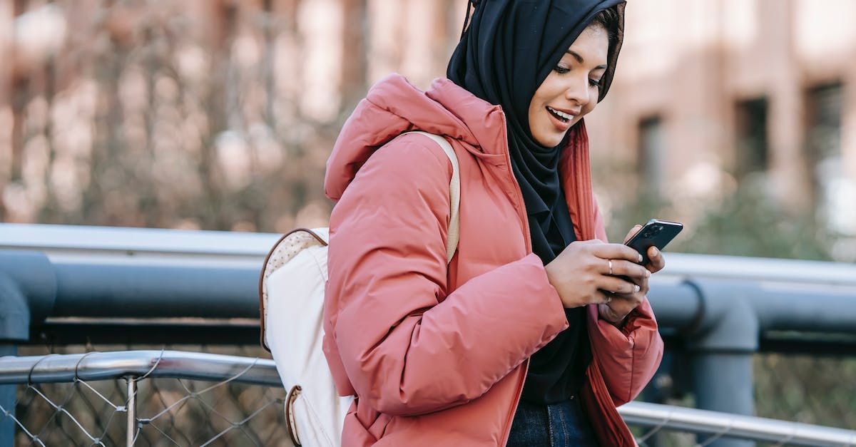 How to check overextension of my subject nations? - Muslim ethnic female in hijab texting message on mobile phone near iron construction on blurred background of building