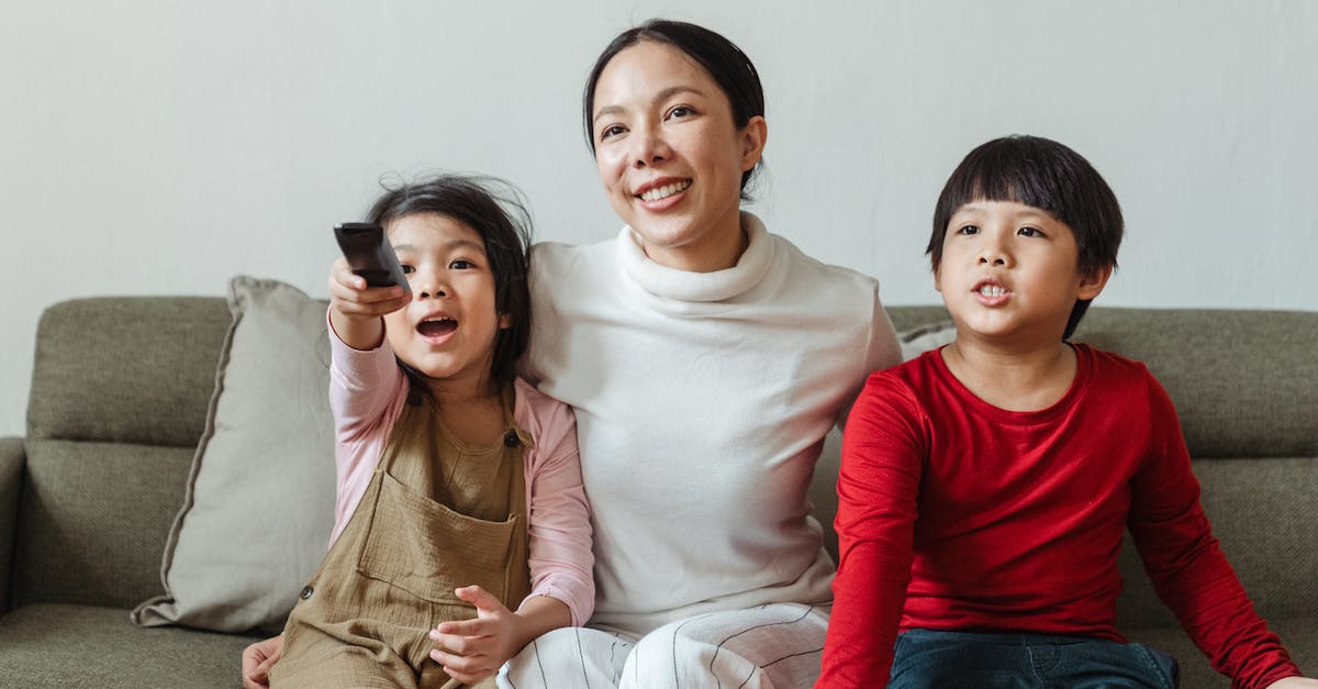 How to choose save device for downloads on Xbox Live - Positive ethnic mother and little children choosing TV channel together