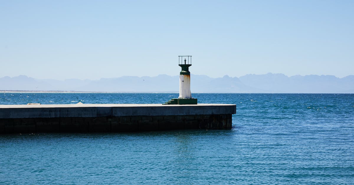 How to clear the lighthouse? - Old lighthouse on pier among rippling water of sea How to clear the lighthouse? - Old lighthouse on pier among rippling water of sea