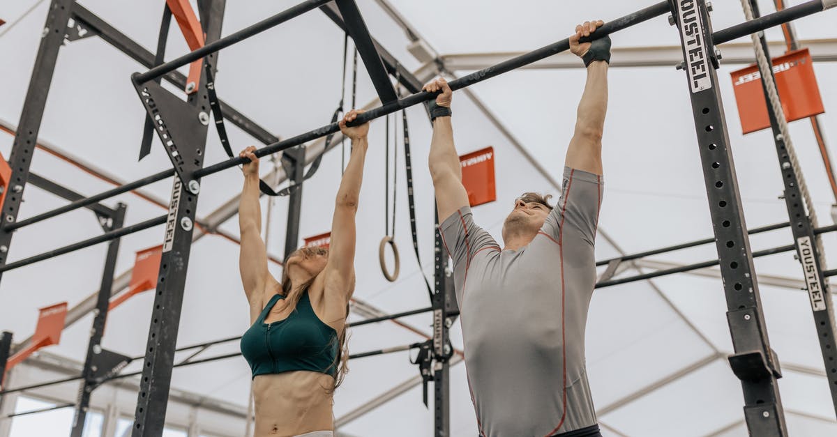 How to climb up when hanging in the Female Ward chapter? - Woman in Black Sports Bra and Black Shorts Hanging on Black Metal Bar