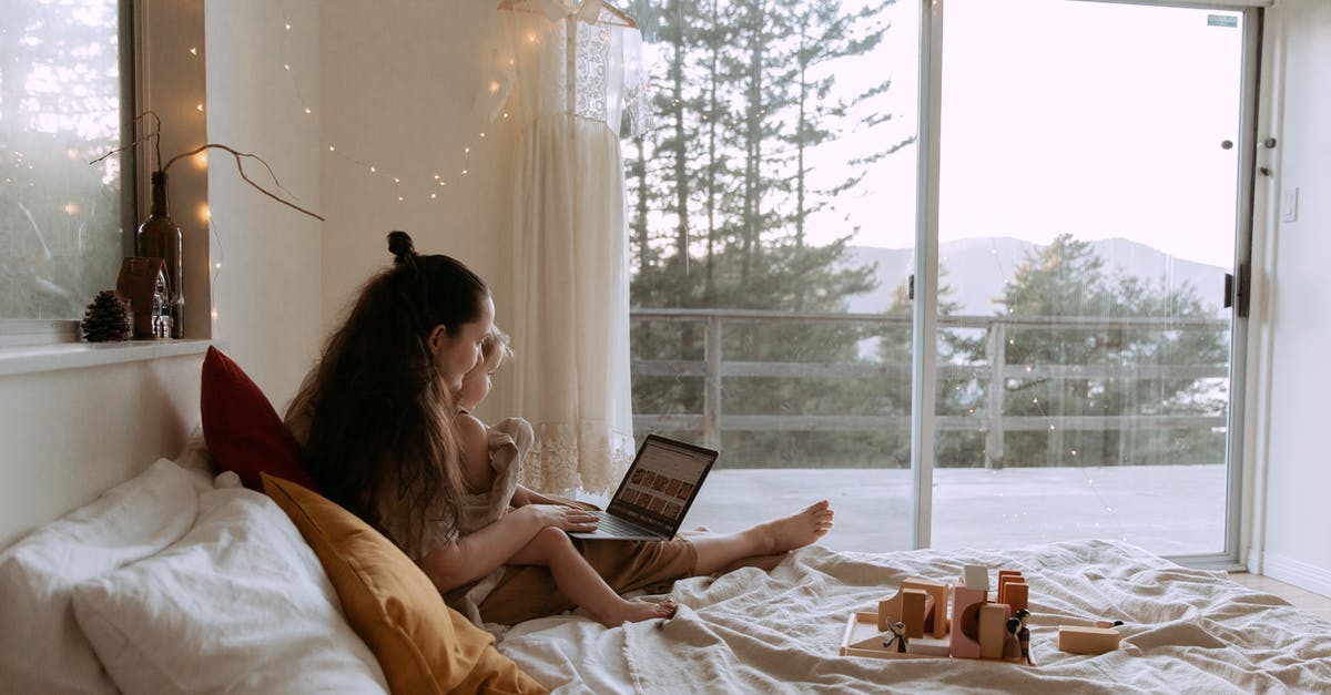 How to connect a small conveyor to a normal one? - Side view of woman with small girl browsing laptop while resting together in bed