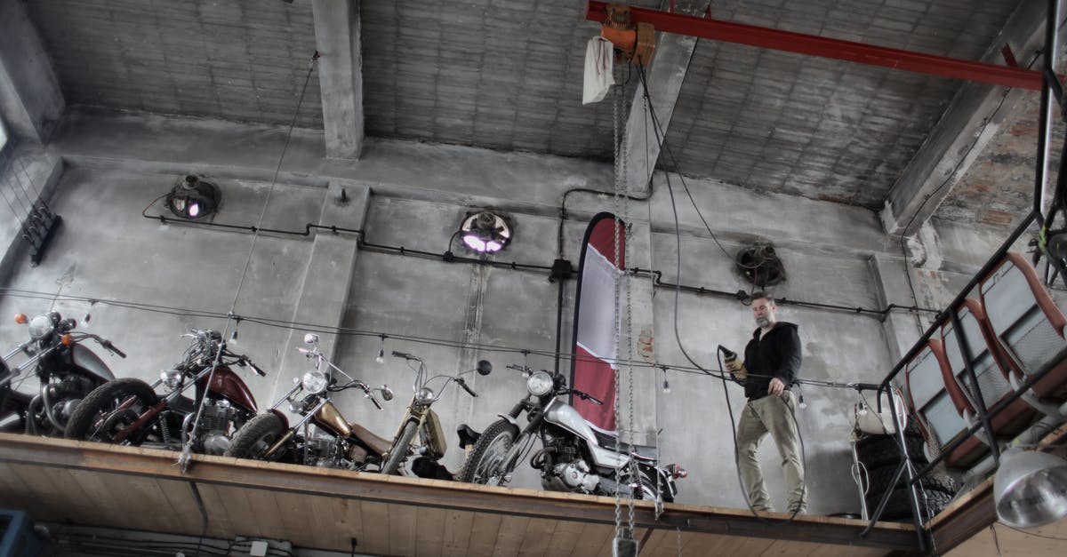 How to control the cargobob and lose the military helicopter - Serious mechanic standing near motorbikes parked together on special platform in garage