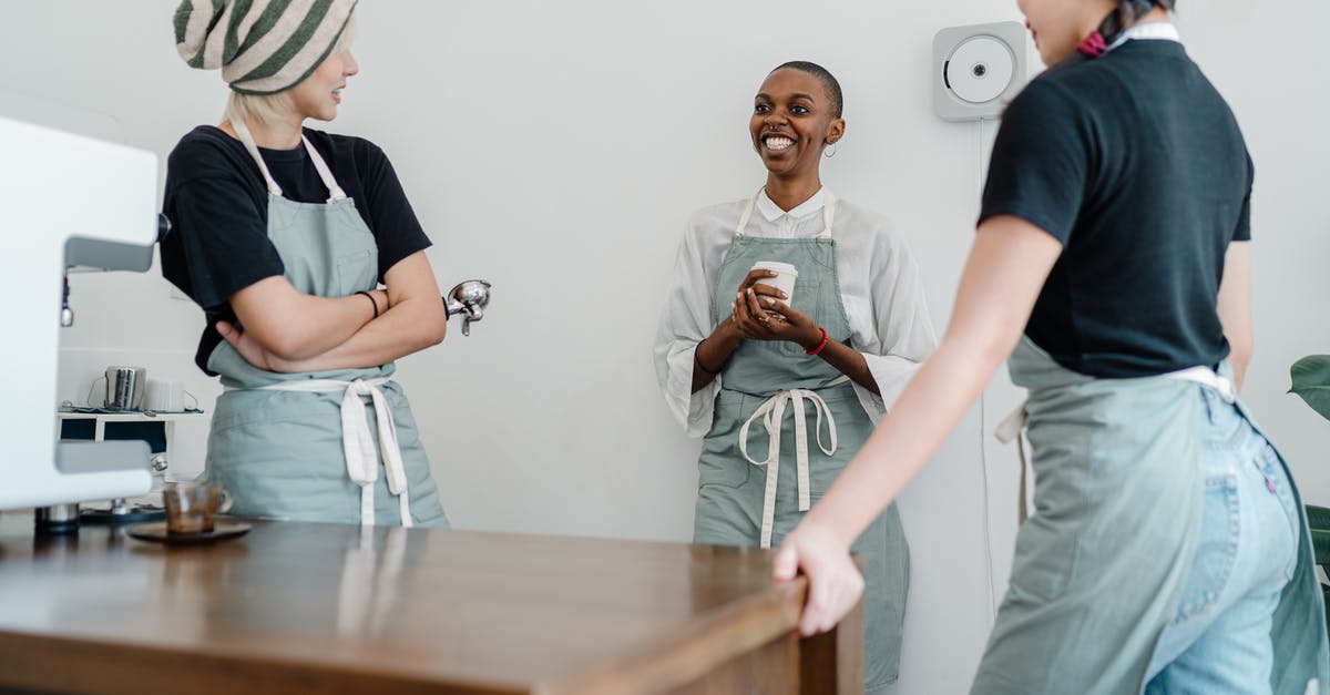 How to counter a team of multiple Torbjörns? - Cheerful young black lady in apron smiling and communicating with colleagues near counter during work in modern coffee shop