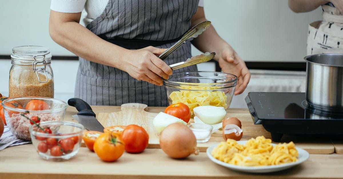 How to counter a team of multiple Torbjörns? - Faceless women in aprons cooking delicious pasta with fresh tomatoes standing at counter in modern kitchen
