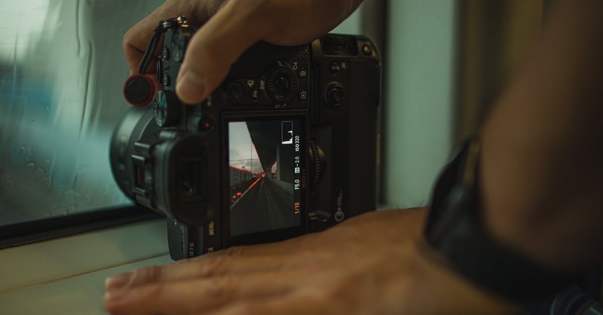 How to create a display - Crop anonymous male photographer demonstrating urban road photo on professional contemporary photo camera while standing in dark room