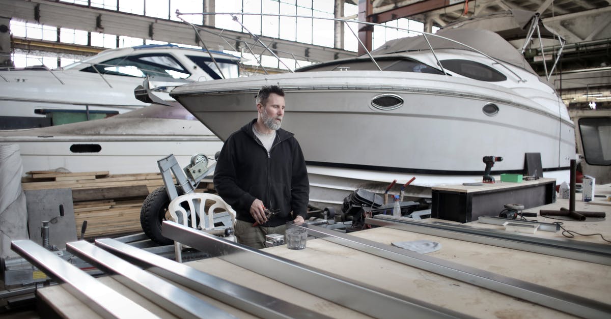 How to create compressed iron without explosions? - Focused adult worker preparing metal details in workshop with yachts