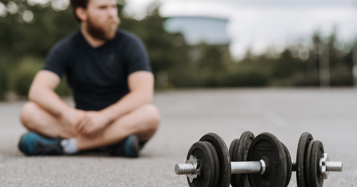 How to determine the correct truck on Election Day: Day 1? - Young male with beard resting after workout on asphalt road with heavy dumbbells on gloomy day in selective focus