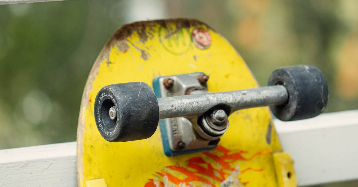 How to determine the correct truck on Election Day: Day 1? - Old skateboard with yellow plywood deck and wheels attached to underside by pair of skateboarding trucks placed near white wooden fence on street in daytime