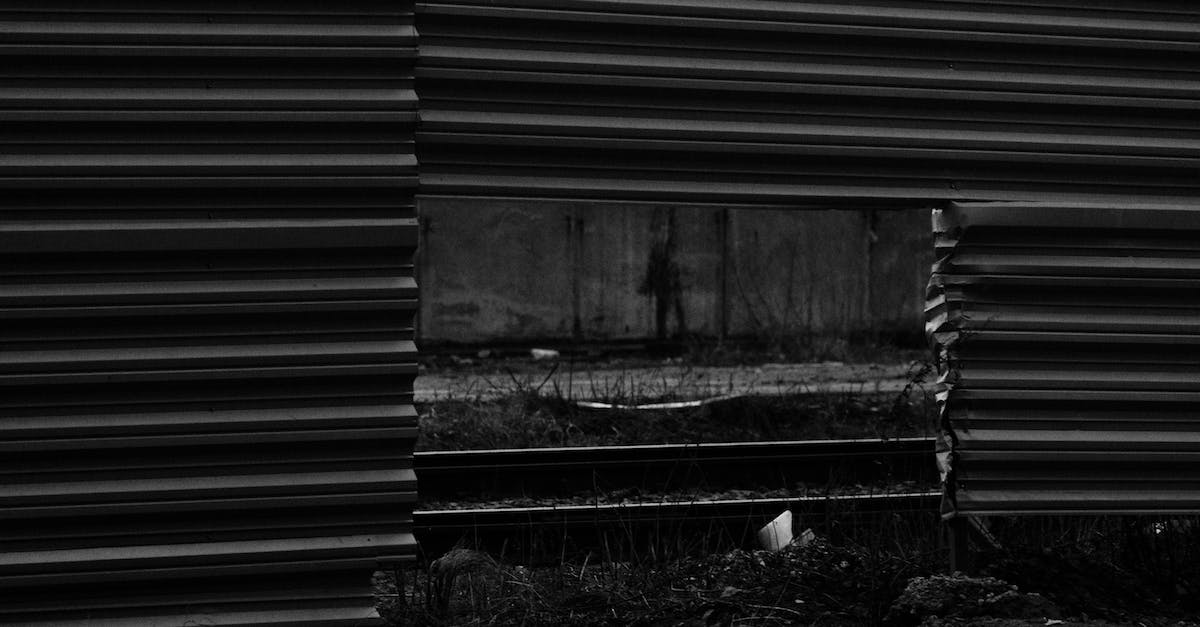 How to dig through "rough hewn diorite wall" - Black and white of automobile road and rails visible through square hole in lower part of enclosure from metallic profile
