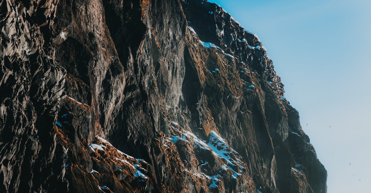 How to embiggen font in Civilisation / Wonders of the World (F7) - Picturesque view of light blue cloudless sky above majestic dark brown steep mountain covered with snow in daylight