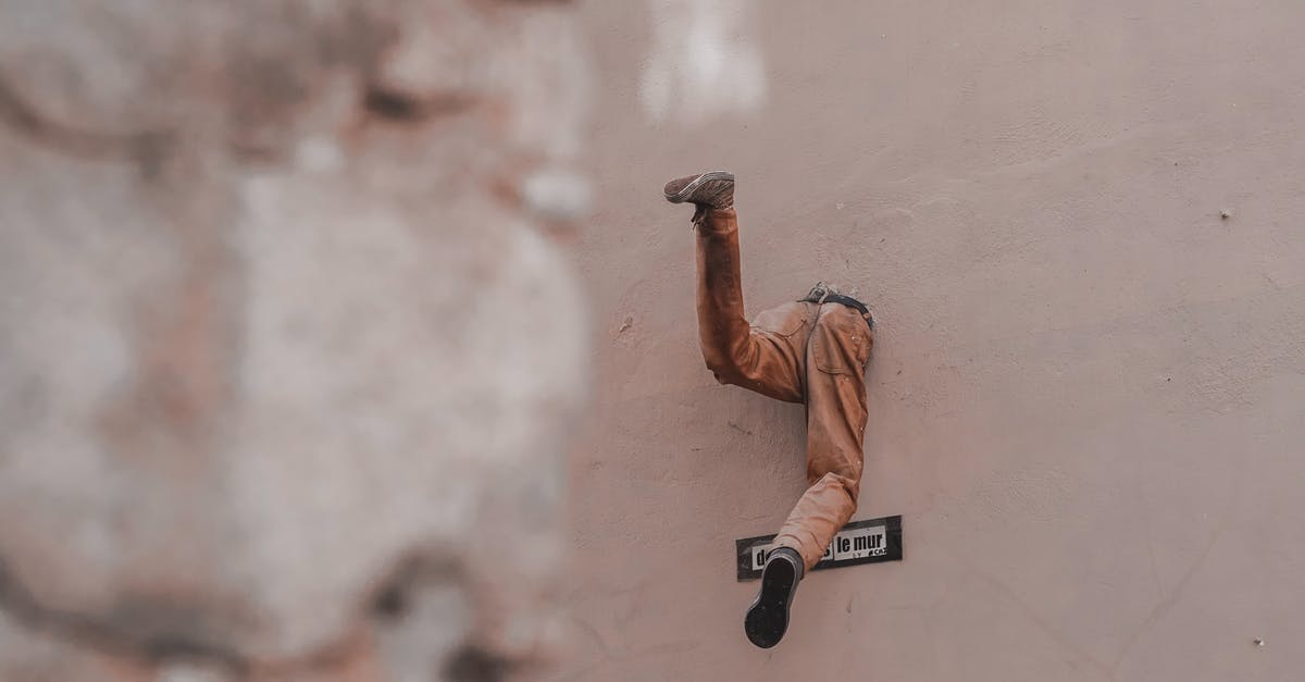 How to escape from zombie grab? - Half body of unrecognizable man escaping through hole in wall