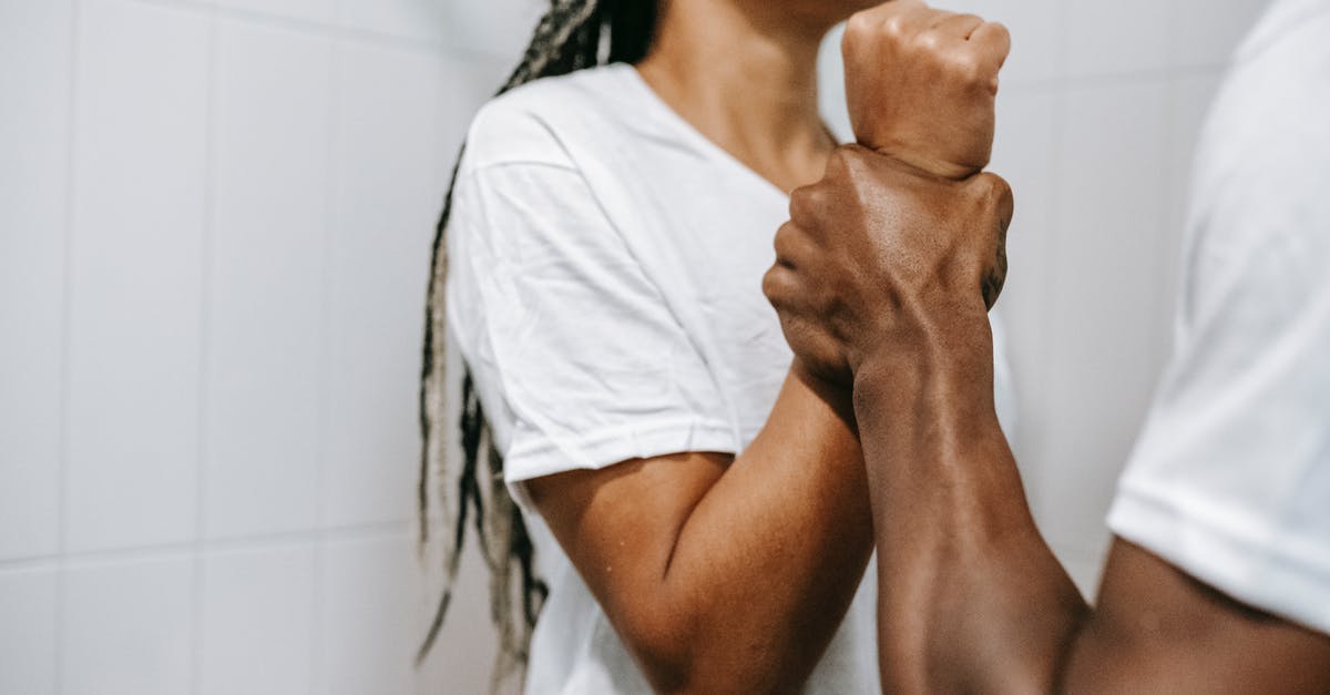 How to fight in close quarters without alerting the guards? - Side view of crop unrecognizable aggressive African American male holding wrist of scared wife while quarreling together in bathroom How to fight in close quarters without alerting the guards? - Side view of crop unrecognizable aggressive African American male holding wrist of scared wife while quarreling together in bathroom