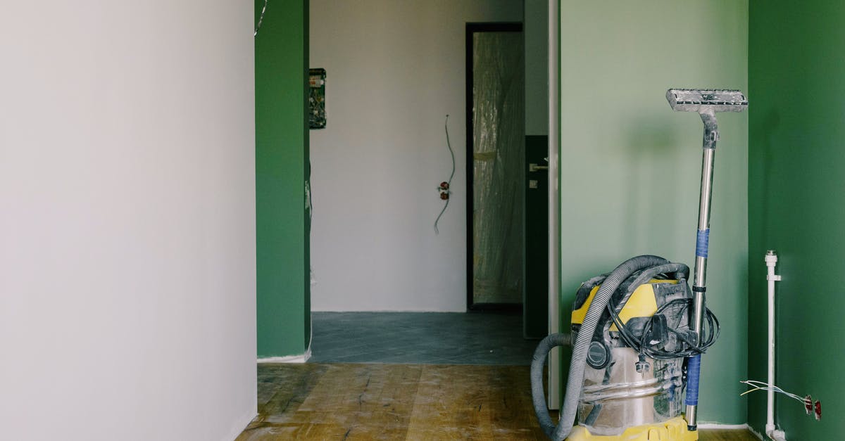 How to fix lack of green light? - Industrial vacuum cleaner placed on dirty parquet in room with green walls and doorway in spacious apartment during repair works