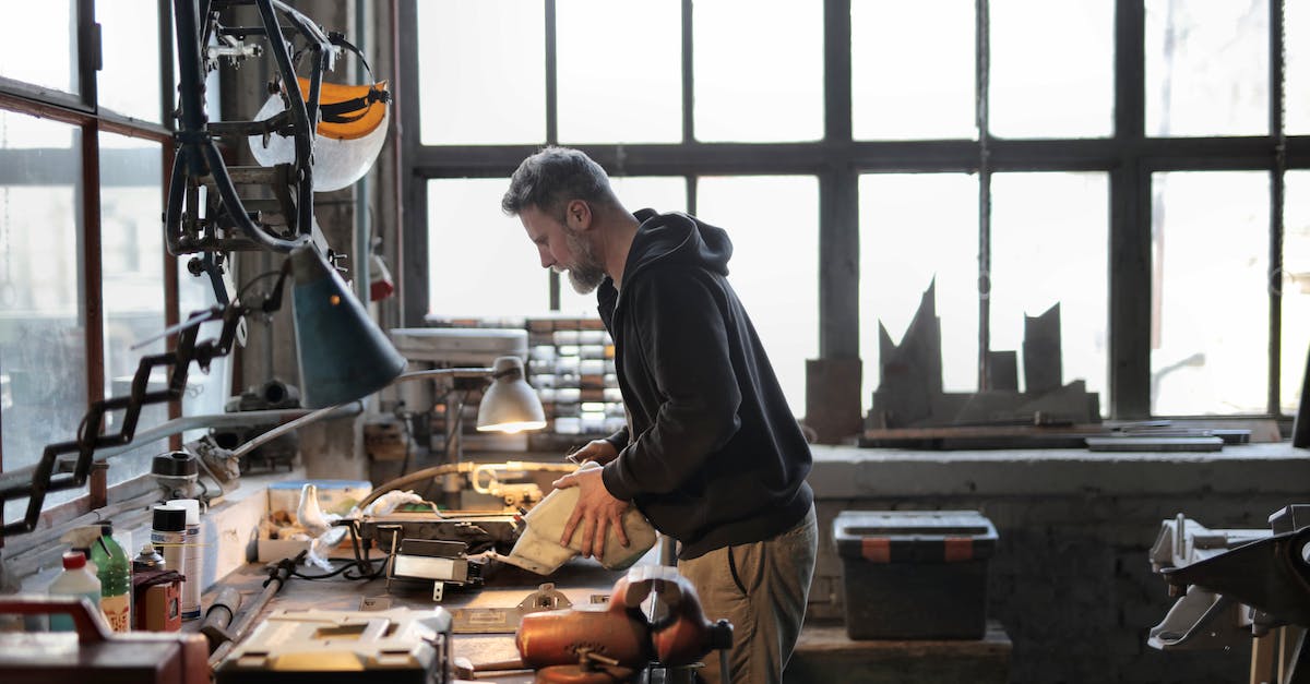 How to fix Mine Craft launcher? [closed] - Side view of male workshop owner standing near messy workbench and fixing metal details while using instruments during work