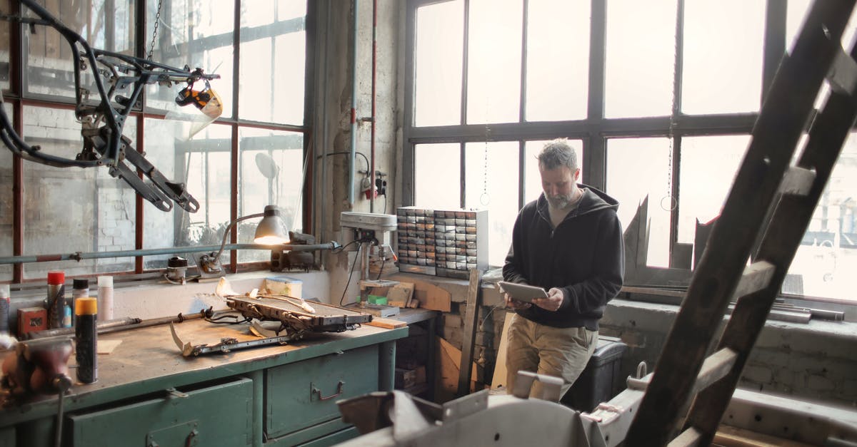 How to fix Minecraft java.lang.nullpointerexception group error? - Adult bearded mechanic in casual wear standing near window in workshop and browsing digital tablet