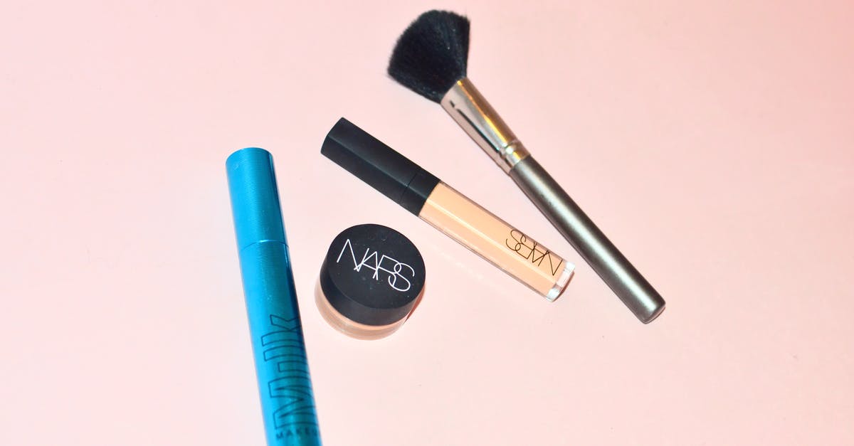 How to funnel Valkyries into the base core? - Top view of professional mascara concealer and cosmetic foundation placed near brush for applying makeup on pink background in studio