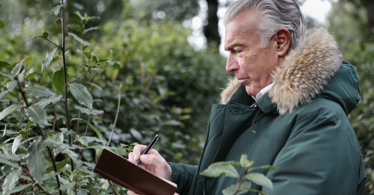 How to get past this old man in Leaf green? - Side view of aged gray haired male in warm outerwear writing with pen in notebook while standing in park