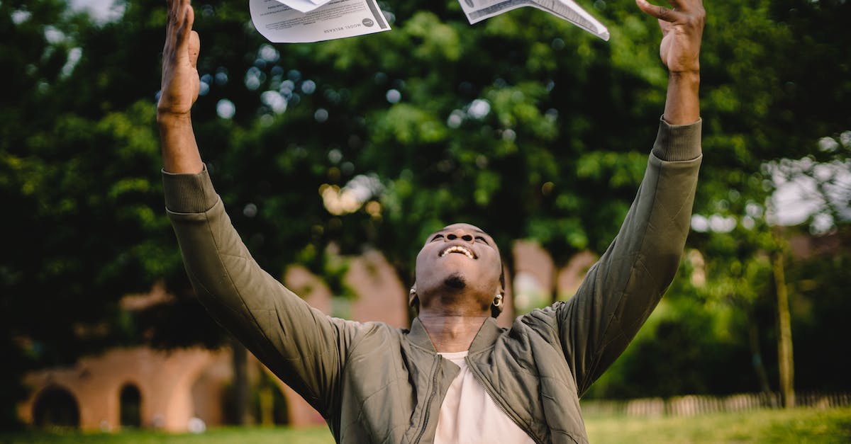 How to get rid of trash? - Happy African American remote worker tossing papers in air happy to get rid of boring paperwork while sitting in green park