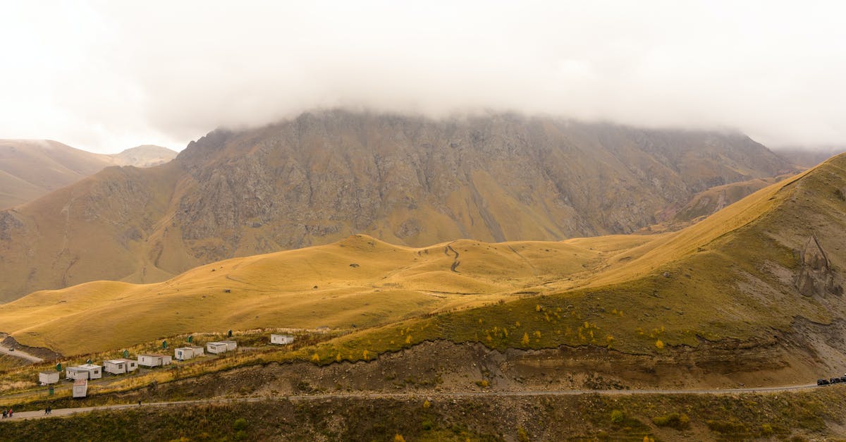 How to get rid of zombie villagers in a world - Picturesque view of green valley in rough rocky highlands with small houses near narrow rural route under cloudy sky