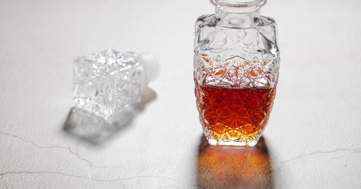 How to get the most expensive items into bottle caps? - From above of open crystal glass jug with alcoholic beverage placed on white table with cracks How to get the most expensive items into bottle caps? - From above of open crystal glass jug with alcoholic beverage placed on white table with cracks