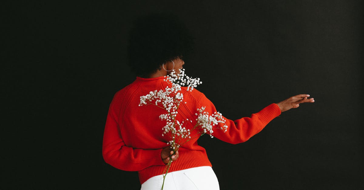 How to hide Minecraft chat? - Back view of sensual black woman in white denim and white red sweater holding Gypsophila flower behind back posing on black backdrop