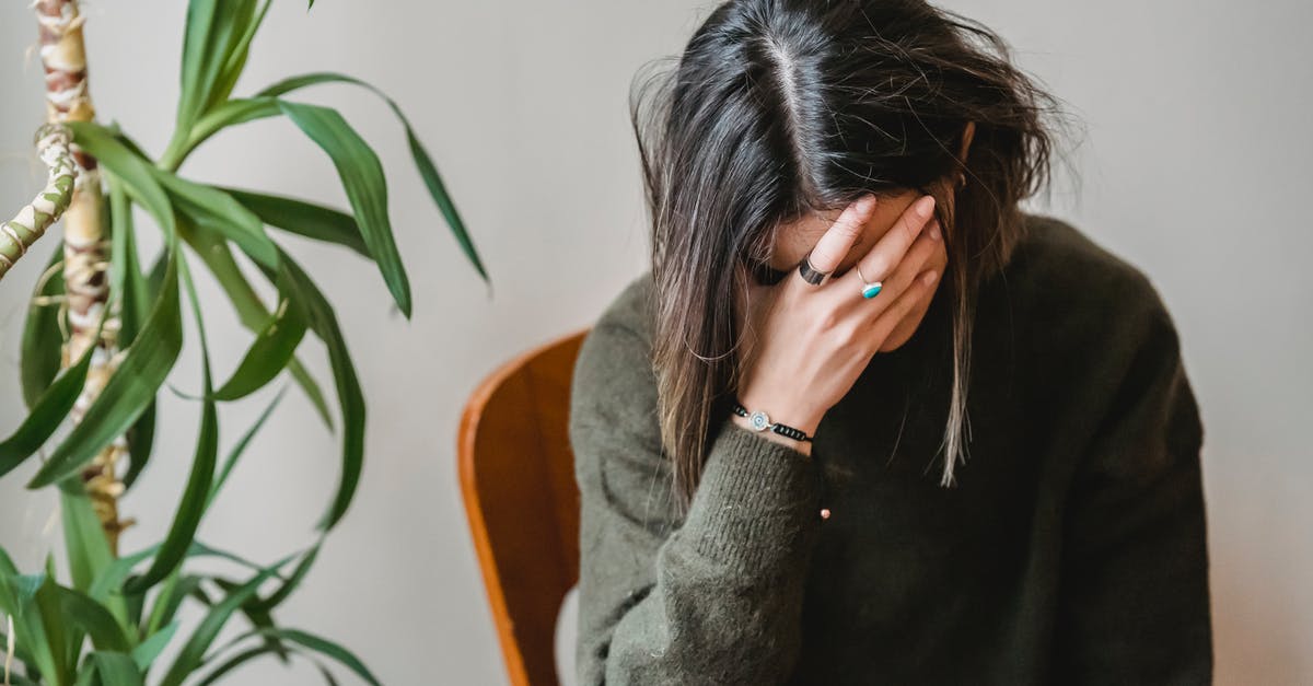 How to hide Minecraft chat? - Unrecognizable young upset female millennial with dark hair in stylish sweater covering face with hand while siting on chair at home