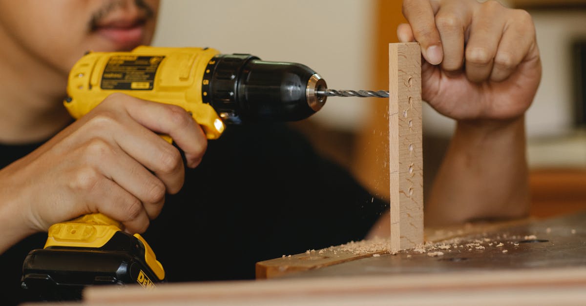 How to improve Power skill? - Crop anonymous male drilling holes in wooden panel while working on table in workshop