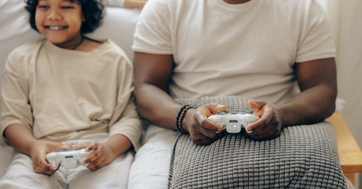 How to install the same game in a Switch console with a parent account and a second Switch console with a child account? - Crop ethnic son and father having fun at home playing video games