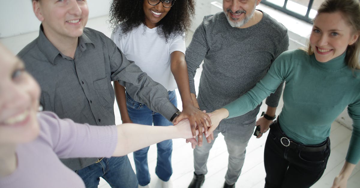 How to join an idle/achievement server? - Happy diverse coworkers of different ages joining hands together in workspace