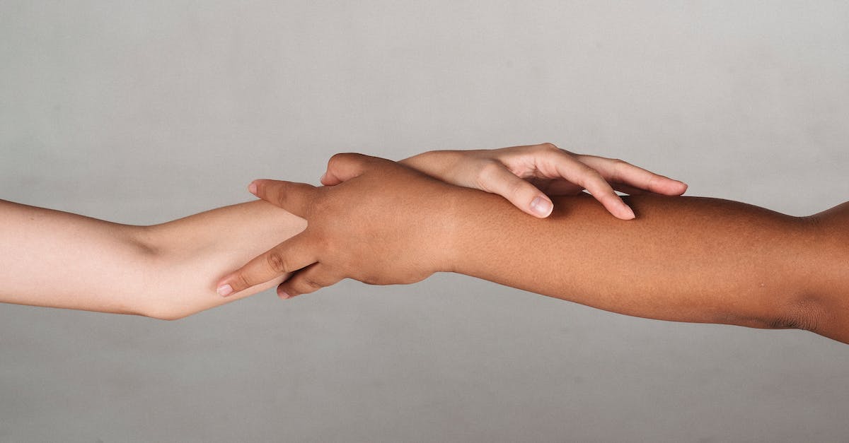 How to join an idle/achievement server? - Crop anonymous multiracial female demonstrating unity and tolerance while reaching hands to each other in studio against gray background