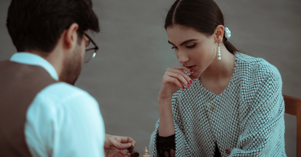 How to kill a player when they touch a block? - Focused ethnic female touching chin while thinking on chess tactic during play with male opponent at gray background How to kill a player when they touch a block? - Focused ethnic female touching chin while thinking on chess tactic during play with male opponent at gray background