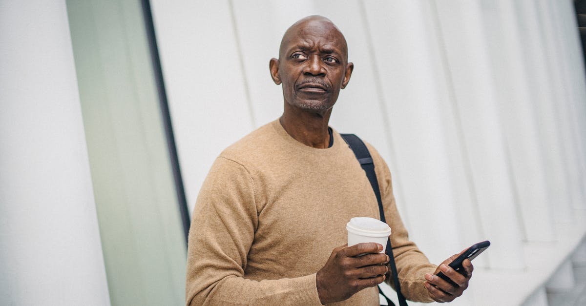 How to link accounts with Mobile on Crusaders of the Lost Idols? - Mature bald black man with smartphone and coffee cup standing on street looking around in downtown How to link accounts with Mobile on Crusaders of the Lost Idols? - Mature bald black man with smartphone and coffee cup standing on street looking around in downtown
