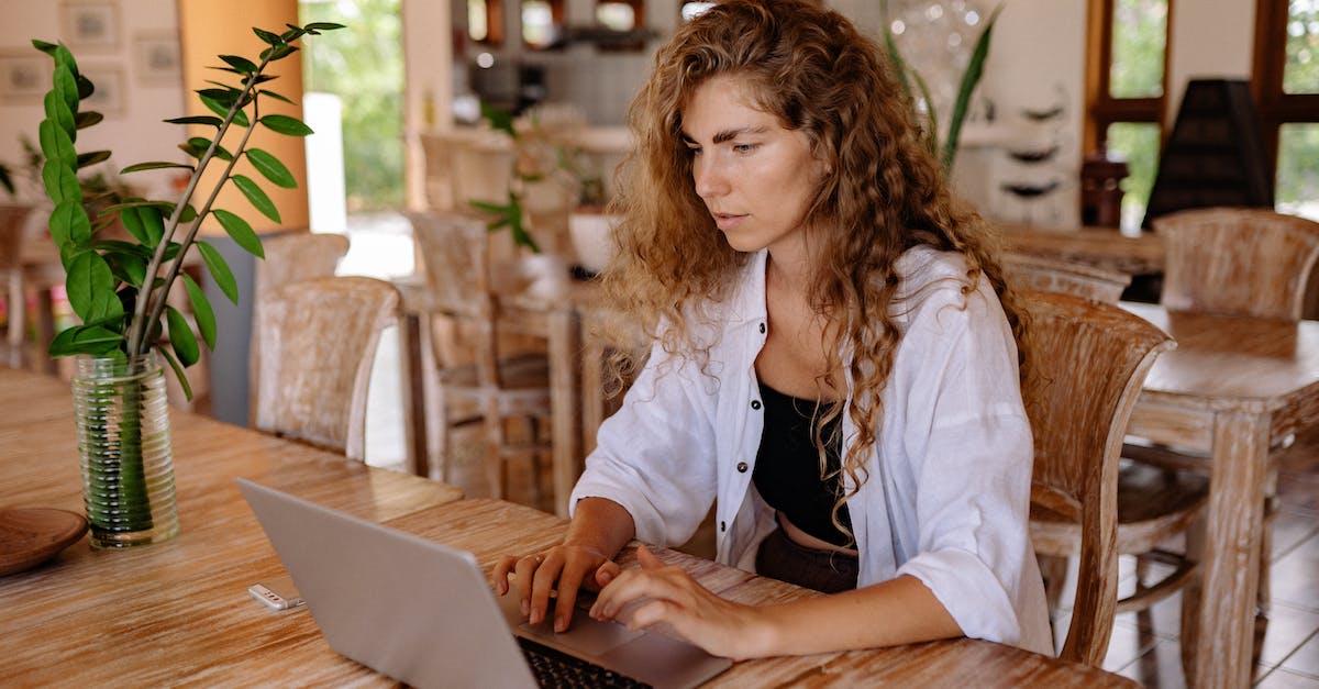 How to make a command block say something only once in Minecraft? - Content female customer with long curly hair wearing casual outfit sitting at wooden table with netbook in classic interior restaurant while making online order