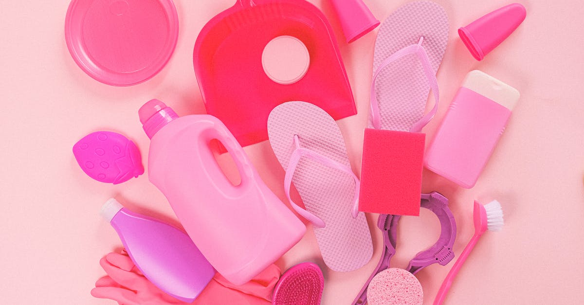 How to make a dispenser shoot infinite creeper eggs - Collection of various plastic detergent bottles and cleaning tools placed on pink background near flip flops and rubber gloves