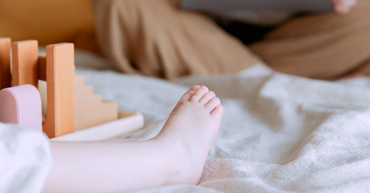 How to make an item only break certain blocks after applying the enchantment and unbreakable parts of the command? [duplicate] - Crop faceless toddler sitting on bed with colorful wooden building blocks while mother sitting with legs crossed doing remote work with laptop on knees on background