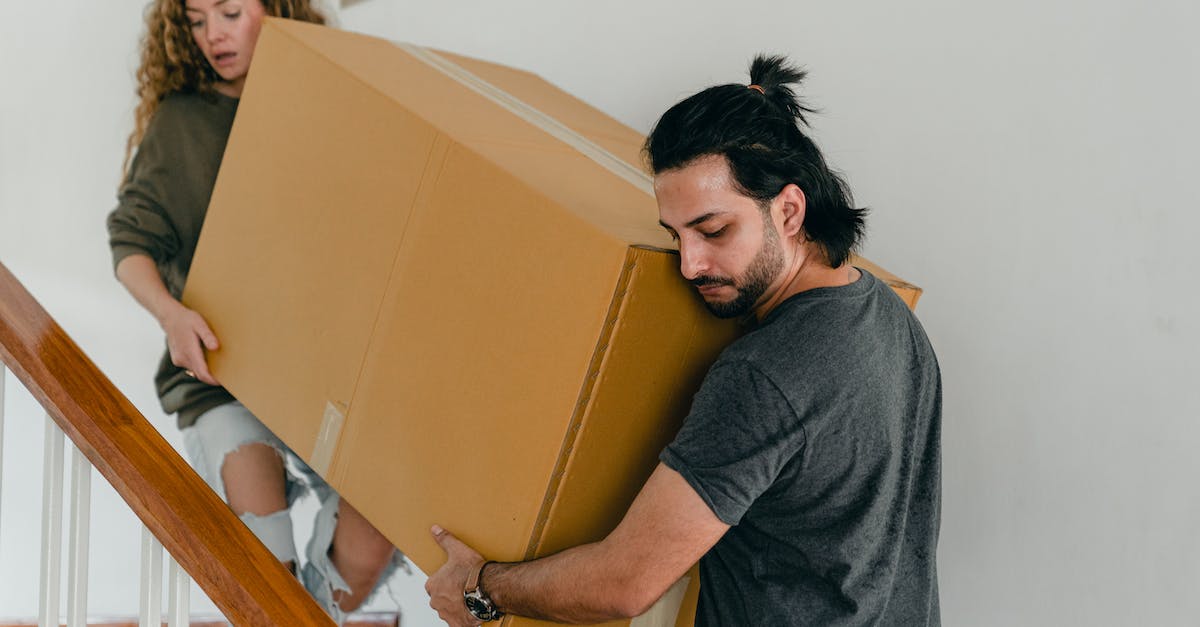 How to move items in a furnace only when there is space? - Focused couple in casual clothes carrying big carton box together down stairs in new house while moving personal items How to move items in a furnace only when there is space? - Focused couple in casual clothes carrying big carton box together down stairs in new house while moving personal items