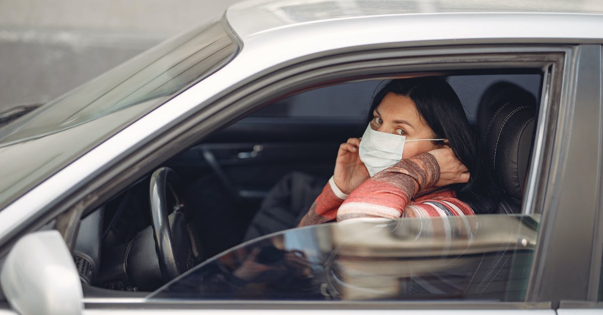 How to open the world map? - Female driver wearing warm outfit adjusting protective facial mask while sitting in auto with opened window during coronavirus pandemic in city and looking at camera