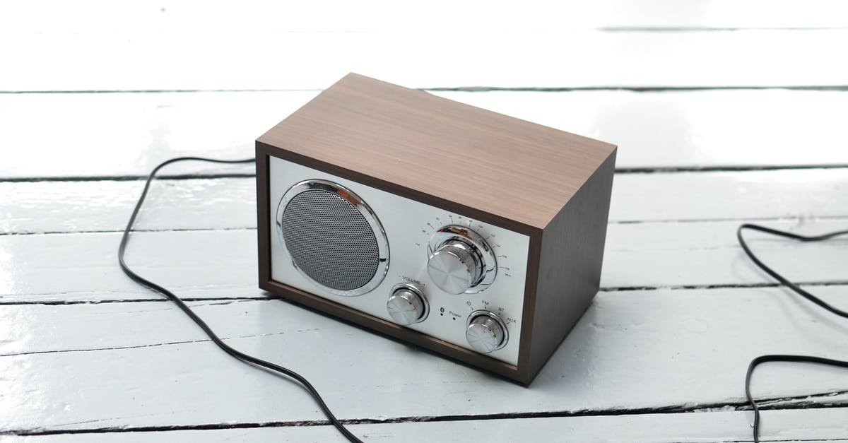 How to output stereo sound from PS4 - From above of vintage styled FM radio with wooden case and steel buttons placed on white lumber table