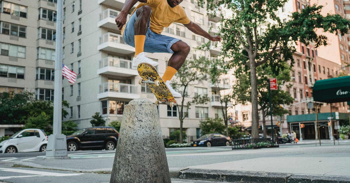 How to perform multiple tricks whilst airborne - Full body athletic African American male skater in summer wear jumping on skateboard on urban street How to perform multiple tricks whilst airborne - Full body athletic African American male skater in summer wear jumping on skateboard on urban street