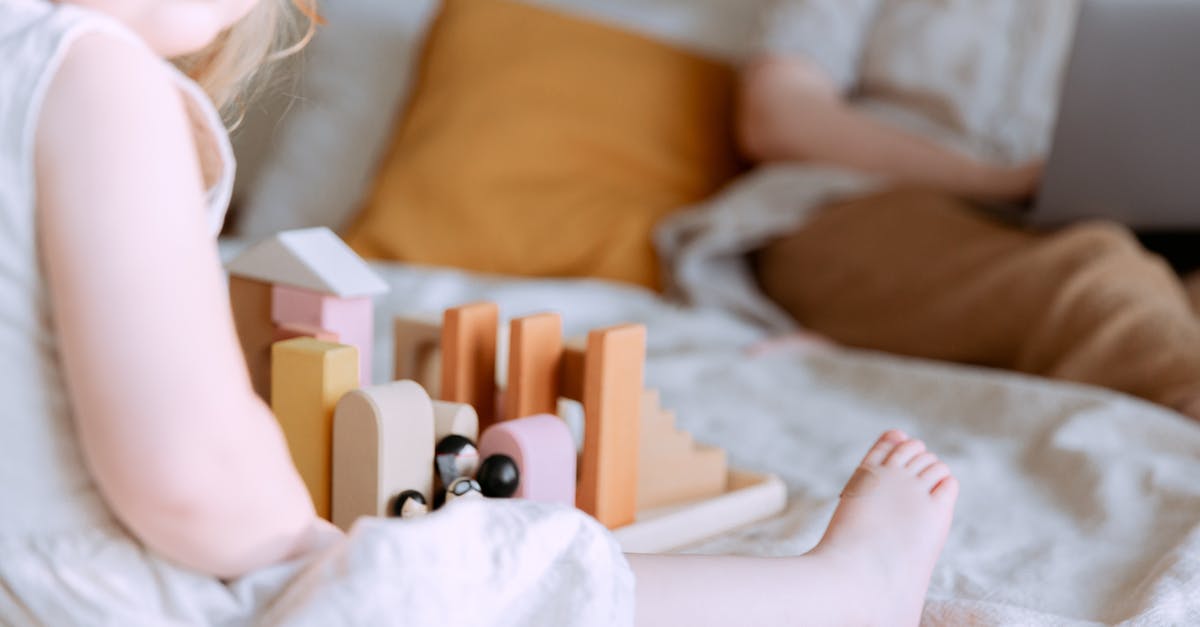 How to play FIFA on a basic laptop without over-heating the laptop? [closed] - Anonymous toddler girl playing with wooden blocks on bed while mother using laptop