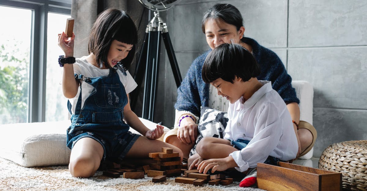 How to play Imperialism 2 with multiplayer manual battles? - Cheerful little Asian siblings sitting on carpet with grandmother and playing tower game during weekend at home
