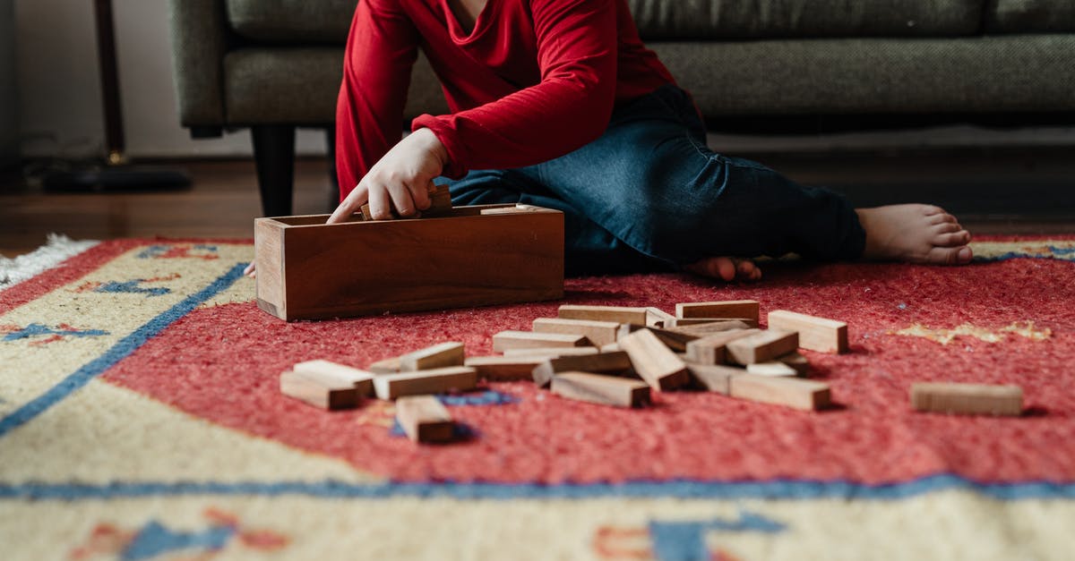 How to play the levels 4 and 5 of the Factorio tutorial in multiplayer? - Ground level of cute kid in casual clothes sitting on floor carpet near cozy sofa and playing in jenga tower game with wooden blocks while spending time at home