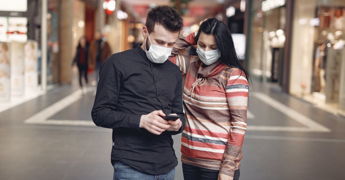 How to prevent the second World War as Hitler - Focused young couple wearing medical masks with smartphone in shopping center