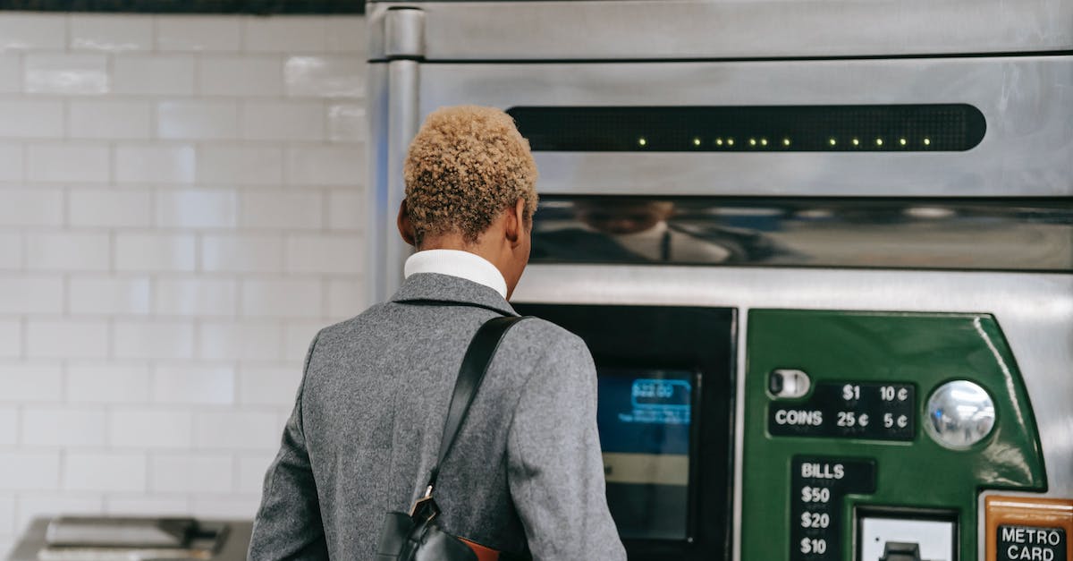 How to purchase zen coins with real money? - Back view of unrecognizable ethnic female manager with short dyed hair in elegant suit buying ticket with electronic machine in subway station