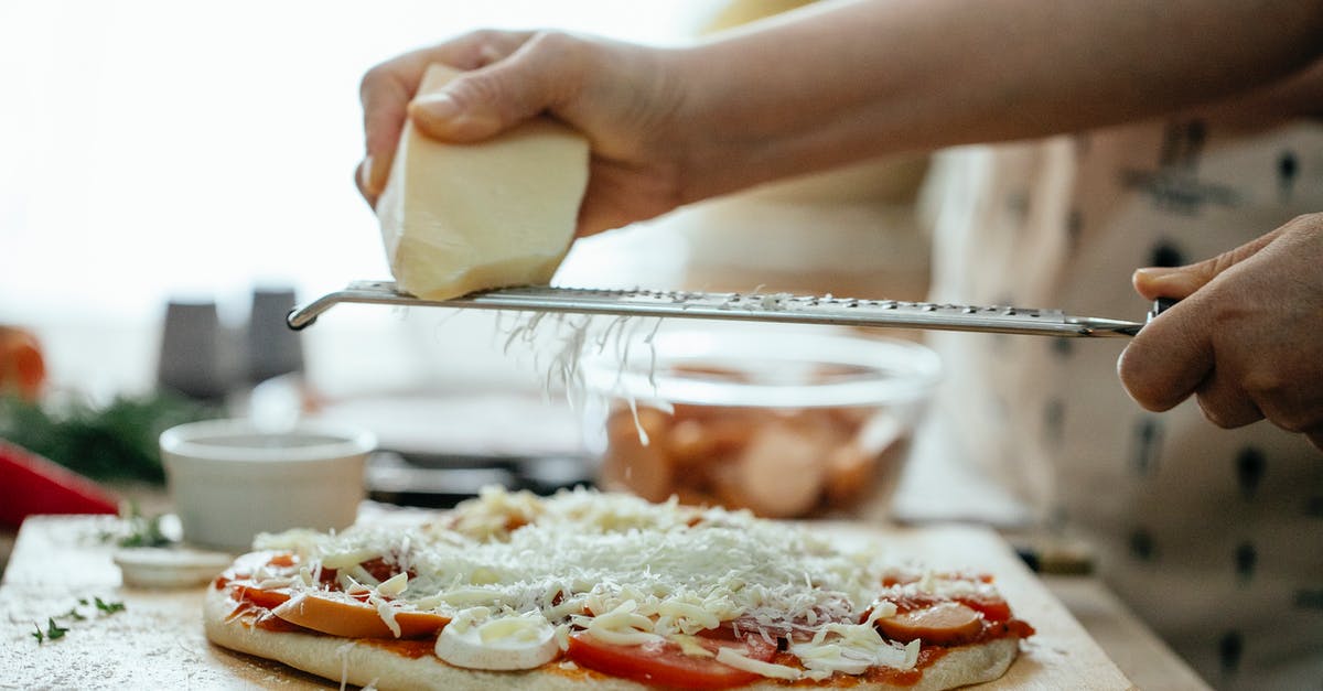 How to put Pokemon into Pokeball? [closed] - Side view of crop unrecognizable person grating piece of hard cheese on palatable homemade pizza in kitchen at daytime