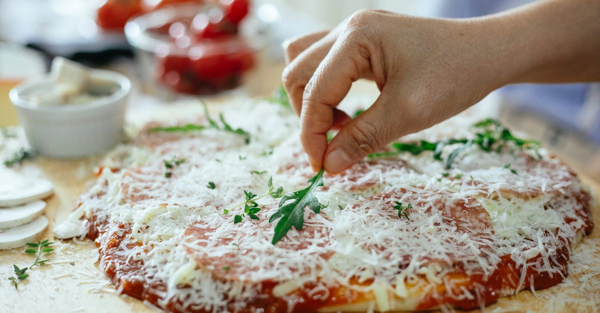 How to put Pokemon into Pokeball? [closed] - Crop unrecognizable person decorating yummy pizza with cheese cover by arugula on wooden table while cooking in light kitchen