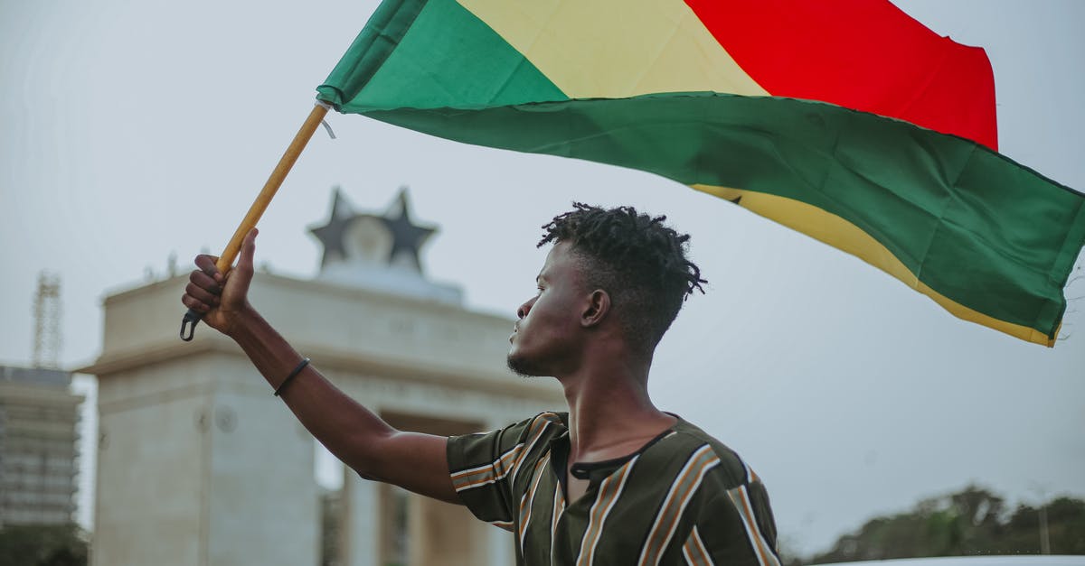 How to raise max sanity? - African male with dreadlocks raising flag of Ghana country with colorful stripes while looking away in town