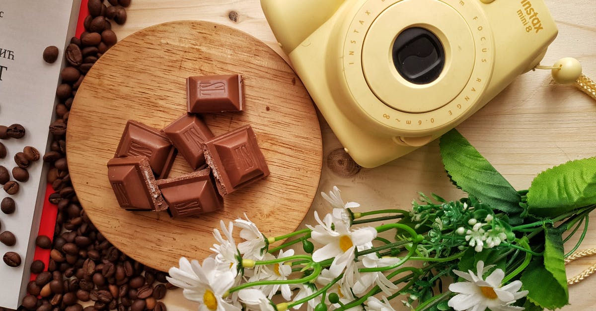 How to read a target bar - Top view of delicious pieces of milk chocolate bar with filling on wooden board near heap of aromatic coffee beans and instant camera with artificial chamomiles on table How to read a target bar - Top view of delicious pieces of milk chocolate bar with filling on wooden board near heap of aromatic coffee beans and instant camera with artificial chamomiles on table